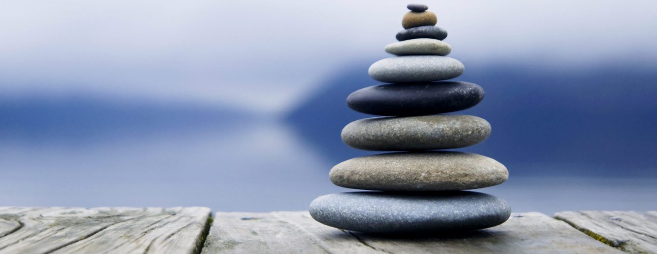 Zen balancing pebbles next to a misty lake.